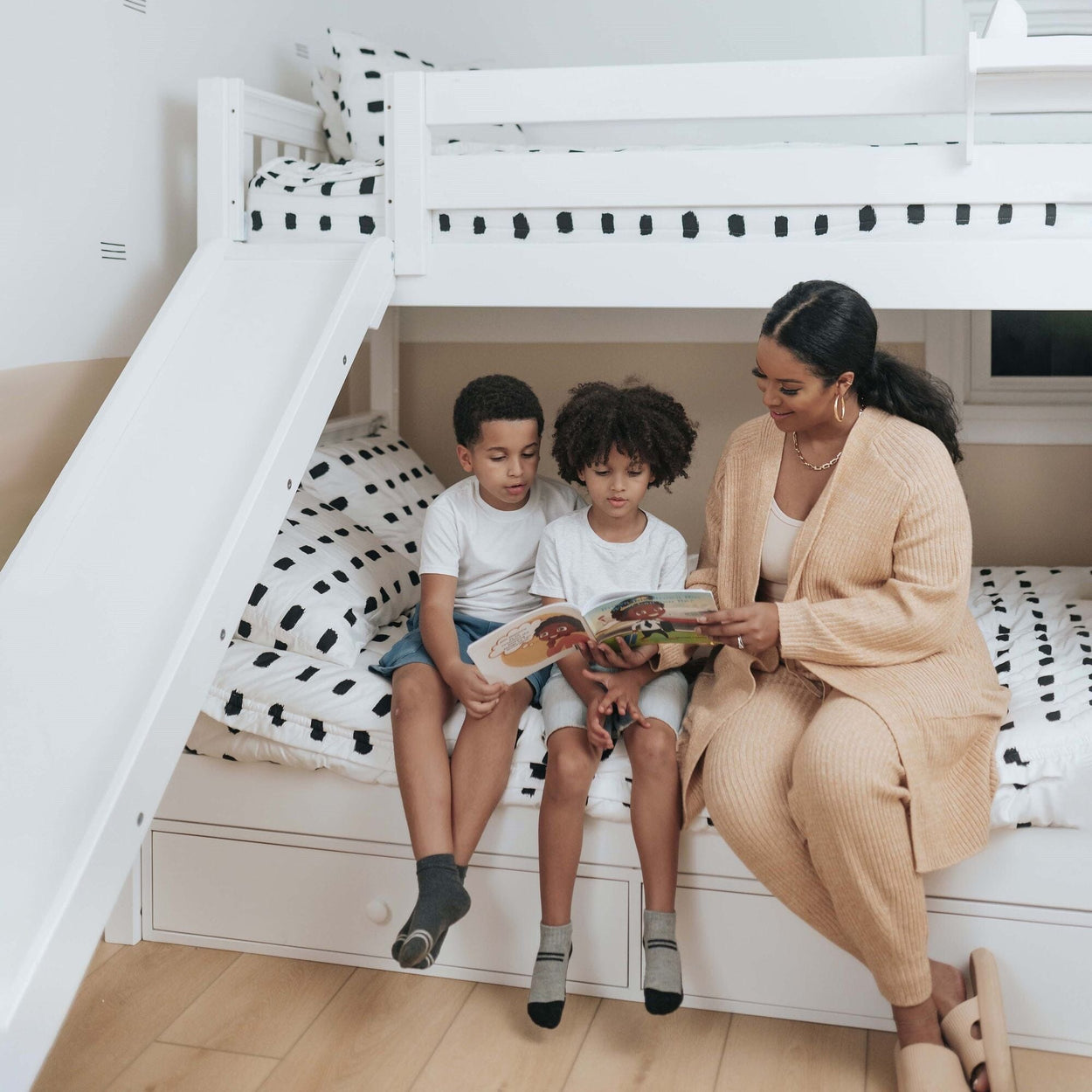 Mother reading a bedtime story to her two children on a bunk bed in a cozy bedroom.
