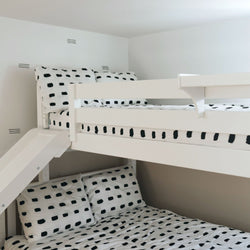 White bunk bed with black and white polka dot bedding, ideal for kids' room decor.