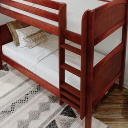 Rustic wooden bunk bed with white bedding and decorative pillows on a patterned rug in cozy bedroom setup.