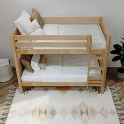 Wooden bunk bed with white bedding and decorative pillows, placed on a patterned rug near a potted plant in a cozy bedroom setting.