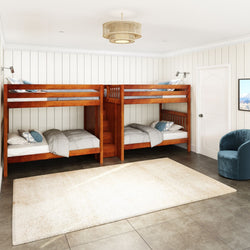 Cozy bedroom interior with wooden bunk beds, blue armchair, and cream rug on tiled floor.