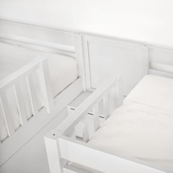 White wooden bunk bed with mattresses and secure railings for children's room.
