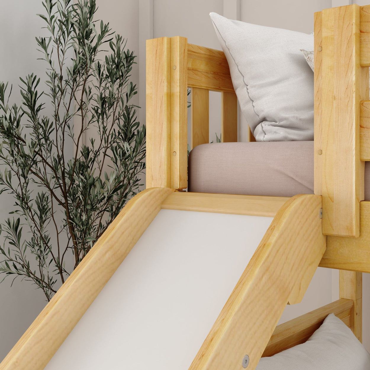 Wooden loft bed with slide and white bedding next to indoor plant in modern bedroom.