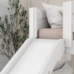 White children's bed with a slide and beige pillow set, next to a potted plant, ideal for playful bedroom decor.