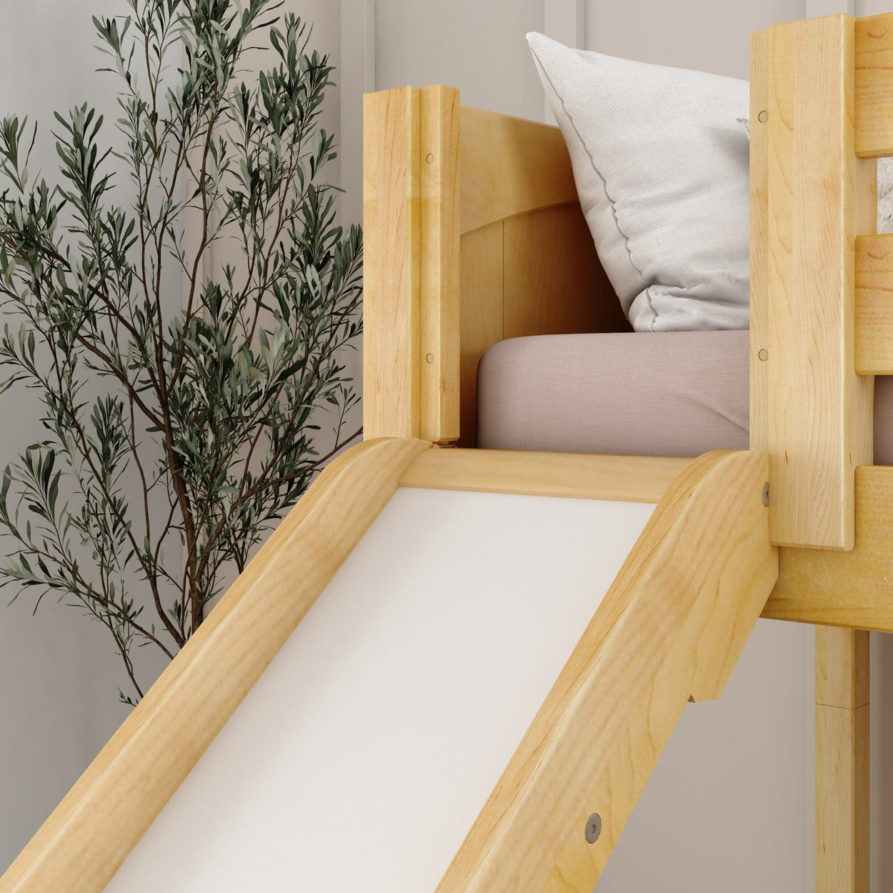 Wooden slide attached to a children's loft bed with pillows, next to a potted plant, in a cozy room.