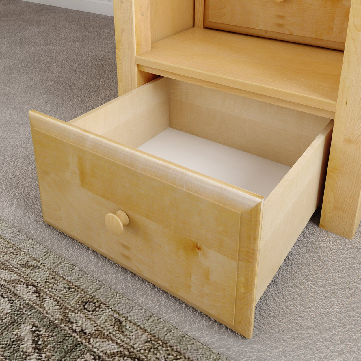 Open light wood drawer on carpeted floor displaying natural wood texture.
