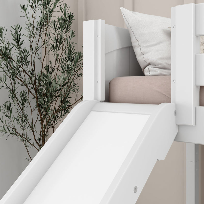 White wooden children's bunk bed with slide, blush mattress and white pillow in a neutral nursery with tall indoor plant