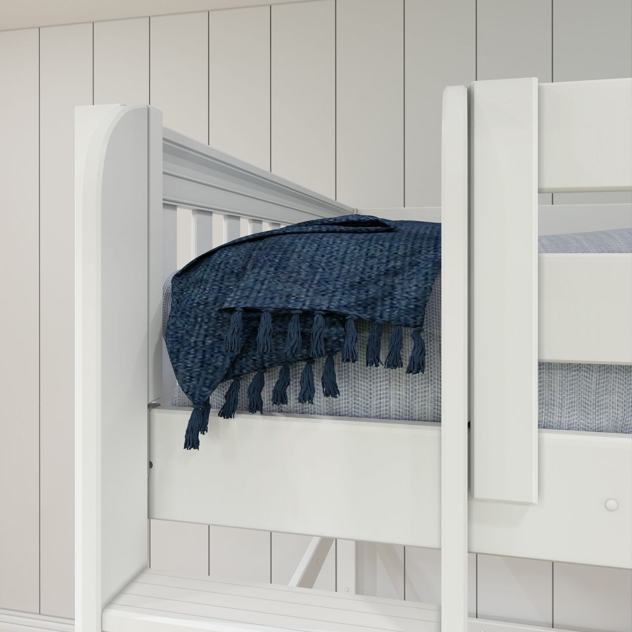 White wooden bunk bed with blue textured blanket and tassels in modern bedroom.