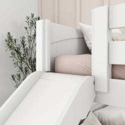 White children's loft bed with slide and cozy bedding near a plant in a modern bedroom.