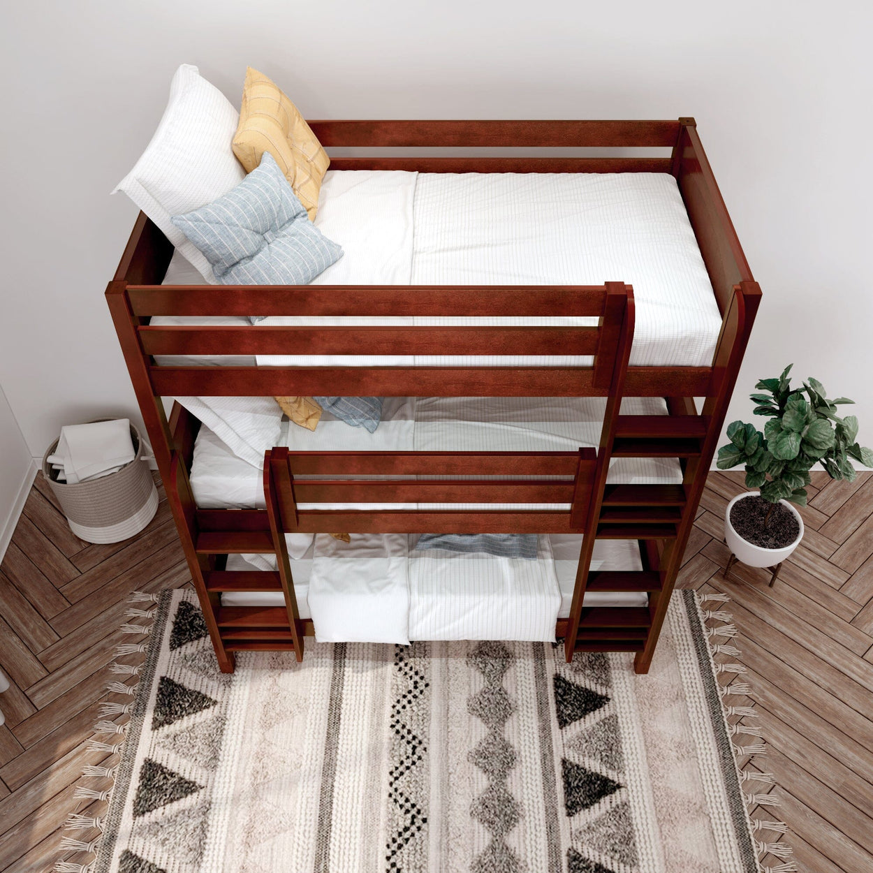 Wooden bunk bed with white and yellow pillows, placed on a patterned rug, next to a potted plant in a cozy bedroom setting.