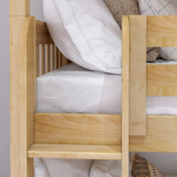 Wooden bunk bed with cozy bedding and pillows in neutral shades.