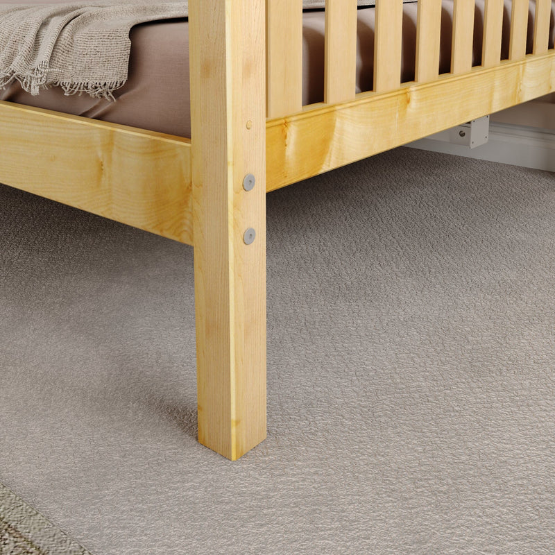 Close-up of natural pine solid wood bed frame corner with slatted headboard, visible bolt fasteners, beige mattress and textured carpet