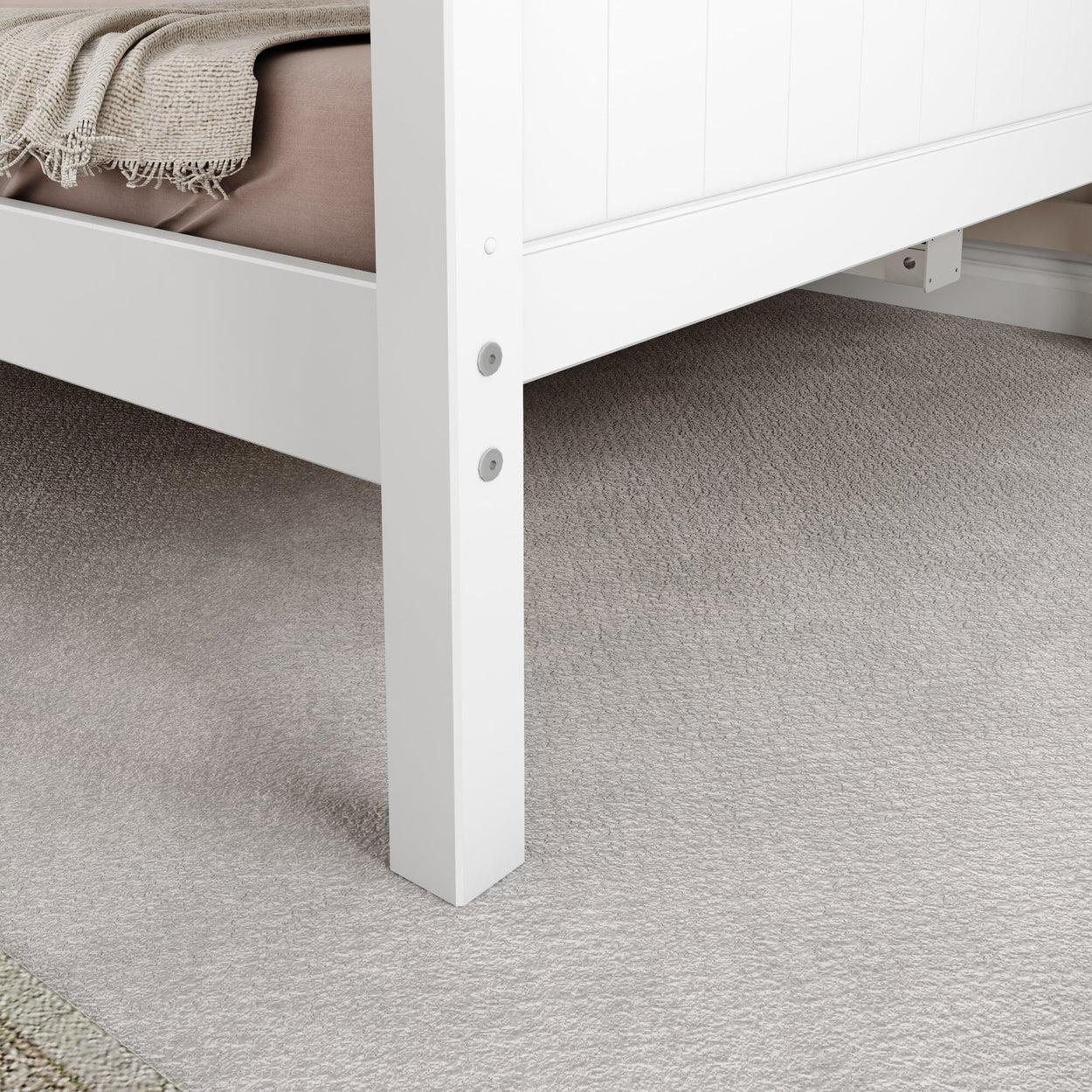 White bed frame leg on soft carpet flooring with beige blanket.