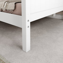 White bed frame leg on soft carpet flooring with beige blanket.