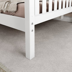 White bed frame on soft beige carpet in a cozy bedroom setting.