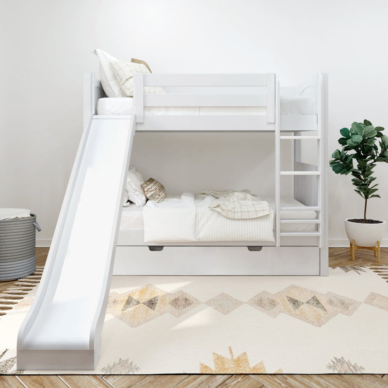 White wooden kids bunk bed with slide and ladder, space-saving trundle drawer and neutral bedding in a modern children's room with patterned rug and potted plant