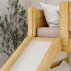 Wooden children's bed with slide and pillows next to a plant in a modern bedroom.