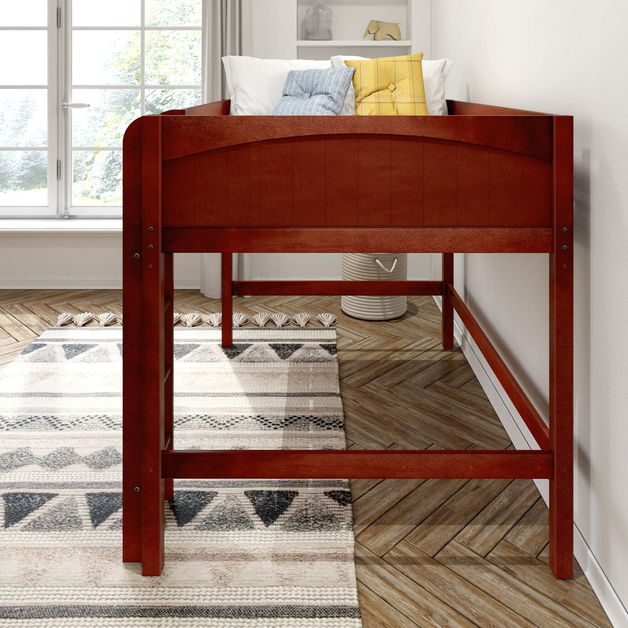 Red wooden twin loft bed in bright modern children's bedroom, space-saving elevated bed with patterned area rug, herringbone hardwood floor and pillows
