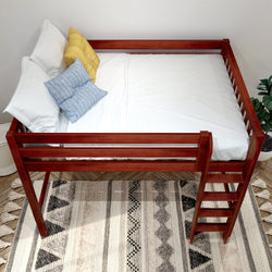 Red wooden loft bed with ladder, white bedding and blue and yellow pillows over patterned boho rug in a modern kids' bedroom