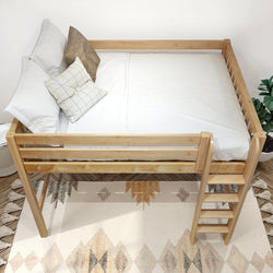 Natural wood loft bed with ladder, white bedding and decorative pillows in a minimalist bedroom with geometric rug and potted plant