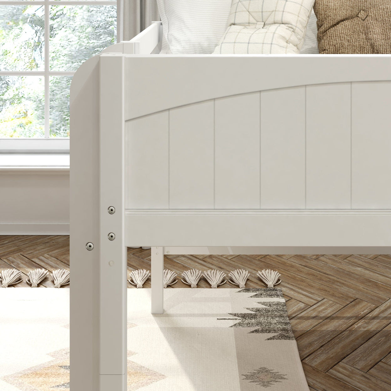 White wooden daybed frame with curved panel headboard, neutral throw pillows, boho rug and herringbone wood floor in sunlit bedroom