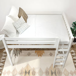 White space-saving loft bed with ladder, crisp white bedding and patterned throw pillows in a modern neutral bedroom with geometric area rug and potted plant