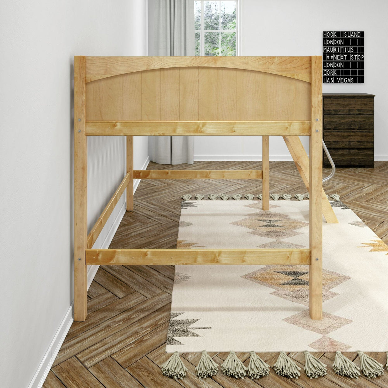 Natural pine twin loft bed frame in minimalist bedroom with herringbone hardwood floor, tasseled boho rug, window and dark dresser