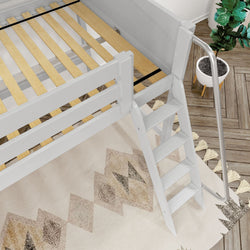 White wooden loft bed with slatted pine mattress support and angled ladder above a geometric southwestern rug, metal safety rail and potted plant on herringbone hardwood floor