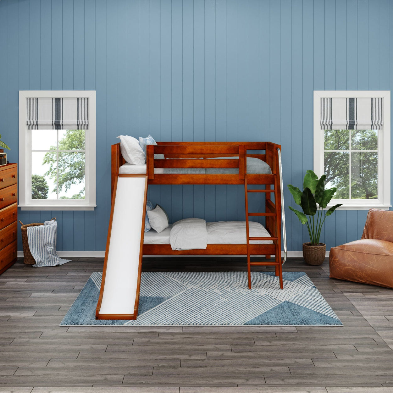 Wooden bunk bed with slide in a blue-walled children's bedroom, featuring cozy bedding, a geometric rug, and modern decor.
