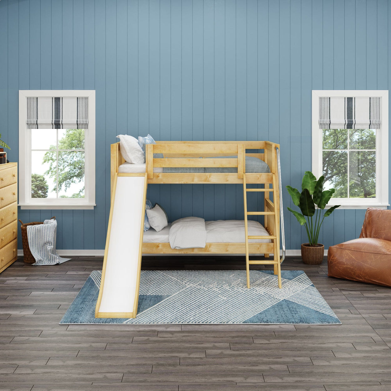 Wooden bunk bed with slide in a blue-themed kids' room featuring decorative pillows, potted plant, and geometric rug.