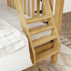 Built-in natural wood bunk bed ladder with wide steps attached to a light pine bed frame next to white plaid bedding in a cozy modern bedroom