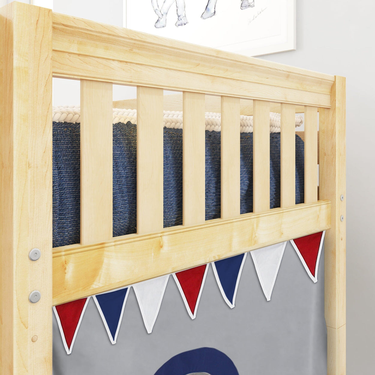 Wooden crib rail with colorful red, white, and blue bunting decor in nursery room.