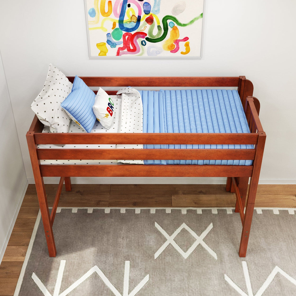 Wooden kids loft bed with blue ribbed mattress pad, white star-patterned sheets and decorative pillows beneath colorful abstract wall art in a modern children's bedroom with geometric rug, ideal space-saving nursery decor