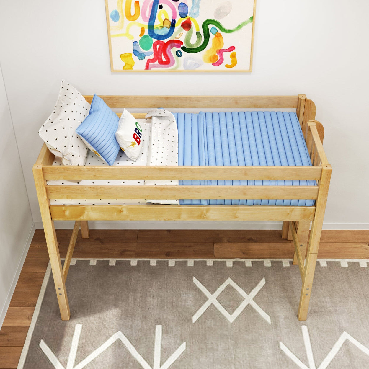 Natural wood toddler loft bed with blue ribbed mattress, star-patterned sheets and colorful pillows under abstract wall art in a modern kids bedroom with geometric rug