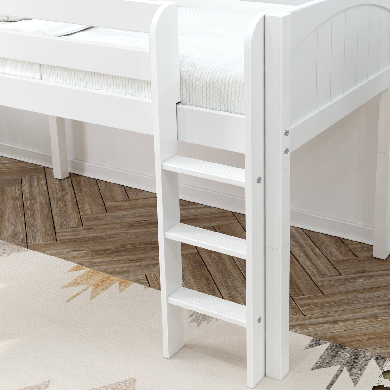 White wooden loft bed ladder on a chevron-patterned wooden floor with a geometric rug.