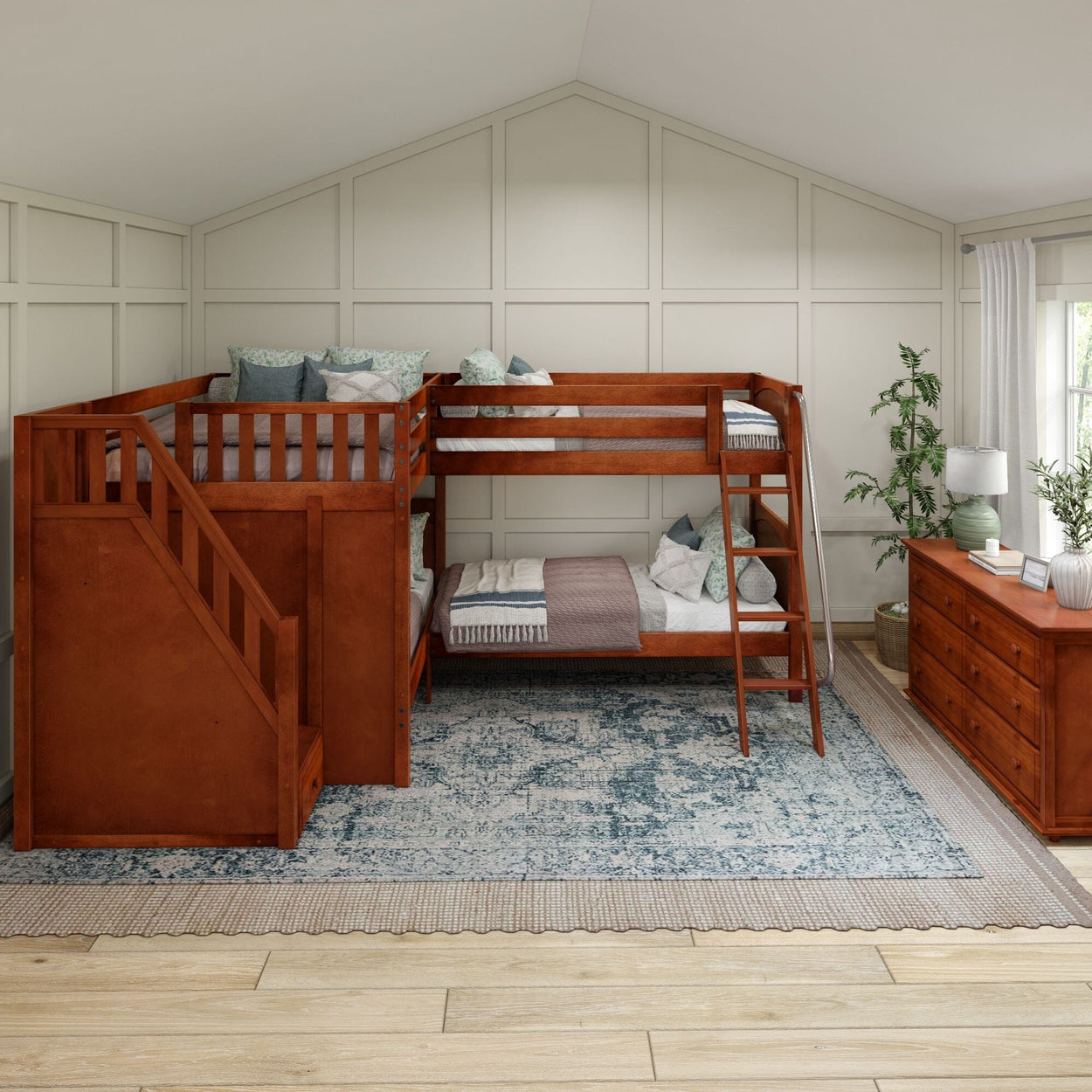 Wooden bunk bed set with stairs and storage in a cozy bedroom with white paneled walls and decorative plants.
