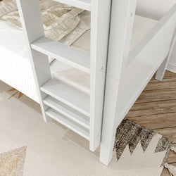 White wooden ladder leading to a cozy bed with plaid and striped blankets on hardwood floor.