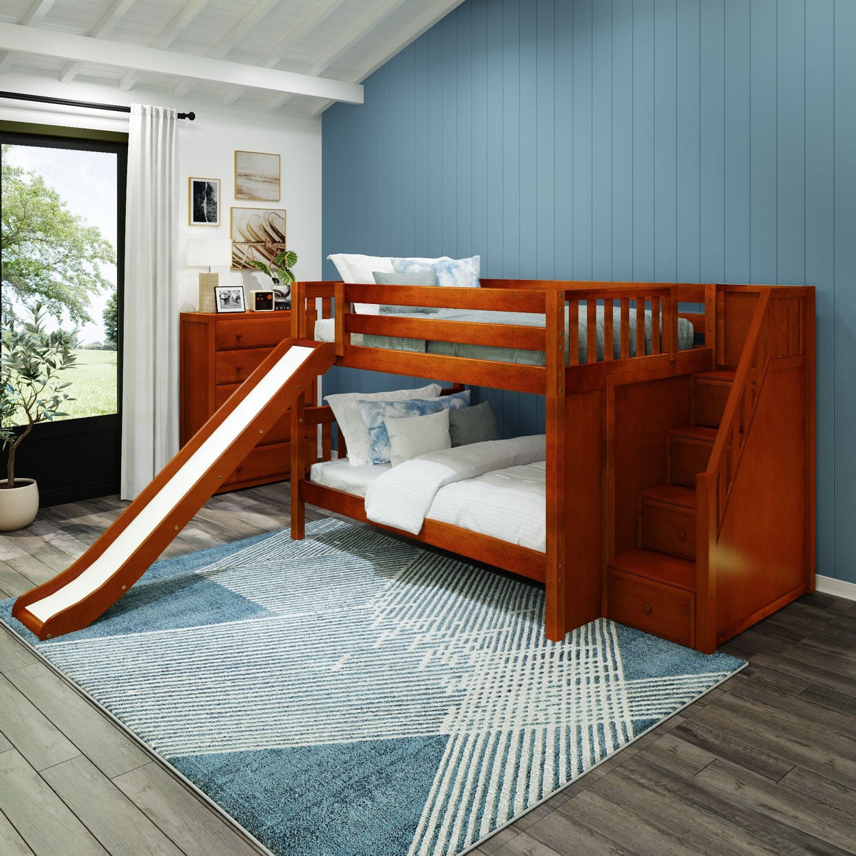 Wooden bunk bed with slide and storage steps in a bright modern bedroom featuring a blue accent wall and stylish decor.