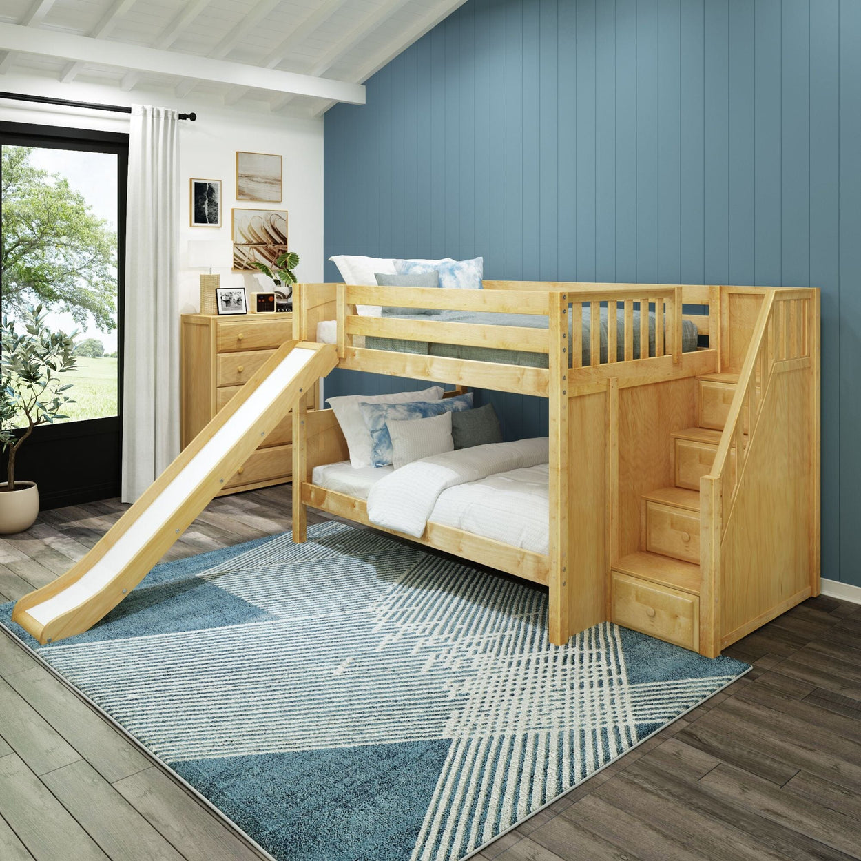 Wooden bunk bed with slide in modern children's room featuring blue accent wall and geometric rug.