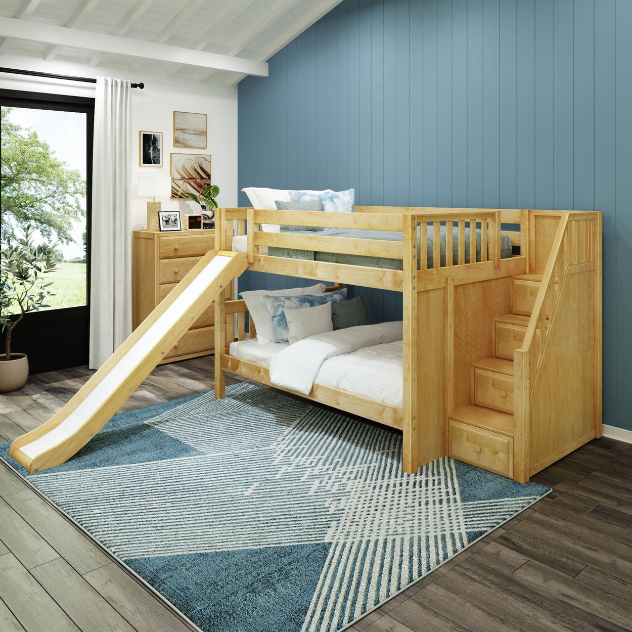 Wooden bunk bed with slide and stairs in a modern kids' bedroom with blue accent wall and large window.