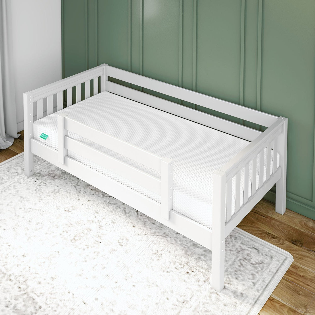 White wooden toddler bed with guard rail in a cozy room setting, featuring green panel walls and a soft area rug.