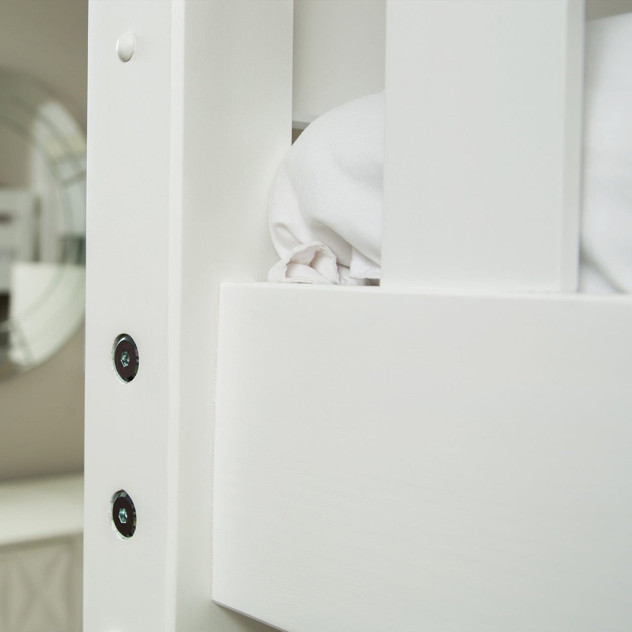 Close-up of white wooden bunk bed frame showing metal bolt hardware, mattress rail and folded white bedding.