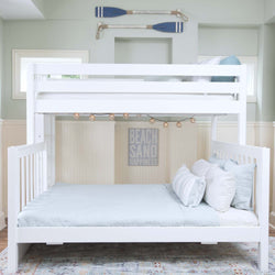 White wooden bunk bed with cozy light blue bedding in a nautical-themed room with beach decor.