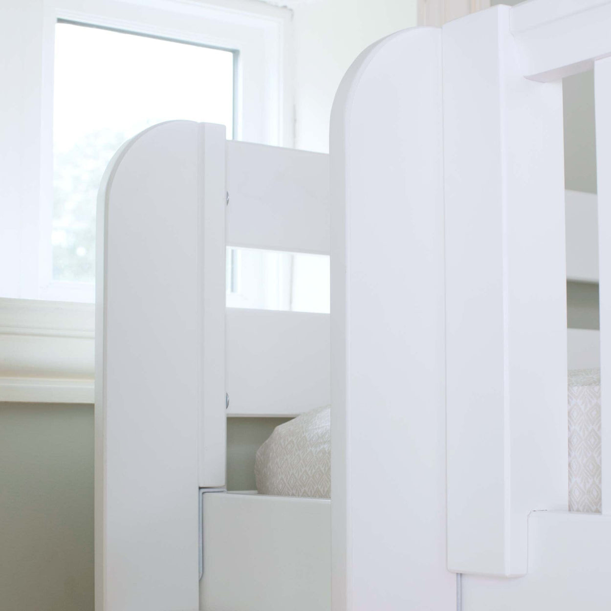 White modern bunk bed frame in bright room near window.