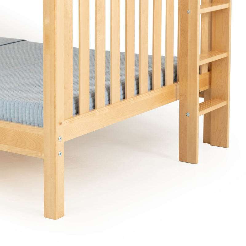 Close-up of natural maple solid wood bunk bed frame showing vertical slatted guardrail, integrated ladder and blue twin mattress cover