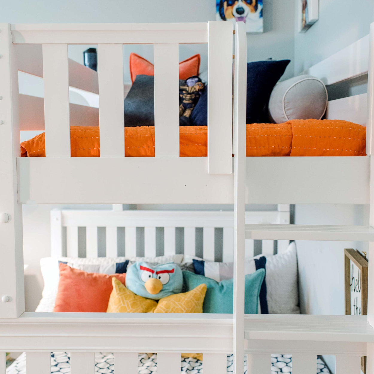 White bunk bed with colorful pillows and orange bedding in a modern kids' room.