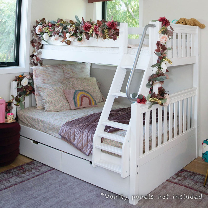 White wooden bunk bed with ladder and under-bed storage drawers, decorated with pink and white floral garland, pastel quilted bedding and rainbow accent pillow in a cozy girls' bedroom