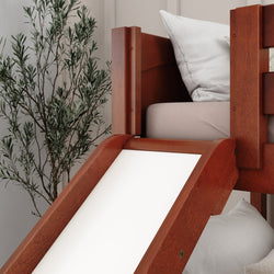 Wooden loft bed with slide and white bedding next to a potted plant in a modern bedroom.