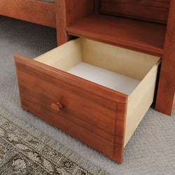 Open wooden drawer under bed for bedroom storage organization.