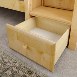 Wooden drawer open under bunk bed showing interior space on carpeted floor.